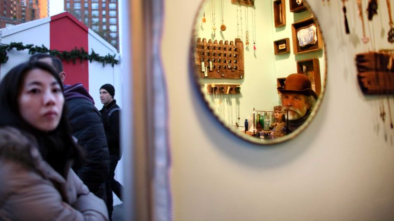 Scott Jordan from Queens, pictured in the mirror, works the Belle Costes booth at the Union Square Holiday Market, Friday, Nov. 21, 2014.