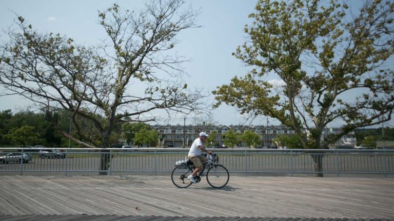 A man rides his bike on the boardwalk.