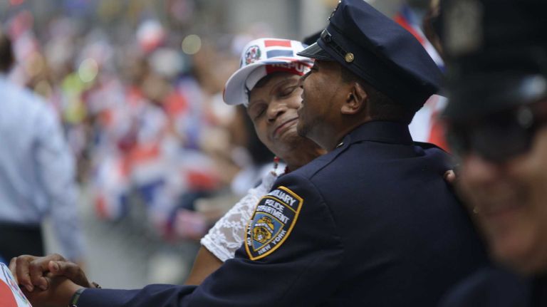 An auxiliary police officer dances with a woman during the 33rd annual Dominican Day Parade along Manhattan's Sixth Avenue, Aug. 10, 2014.