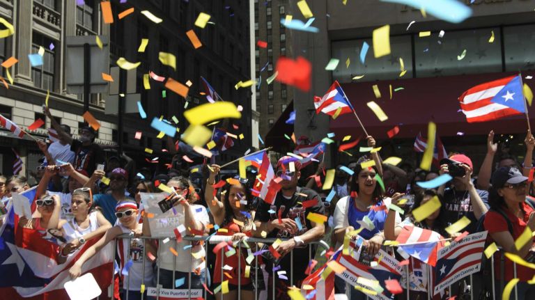 Revelers cheer and wave flags along Fifth Avenue during the 57th annual National Puerto Rican Day Parade in Manhattan on Sunday, June 8, 2014.