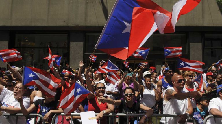 Revelers cheer and wave flags along Fifth Avenue during the 57th annual National Puerto Rican Day Parade in Manhattan on Sunday, June 8, 2014.