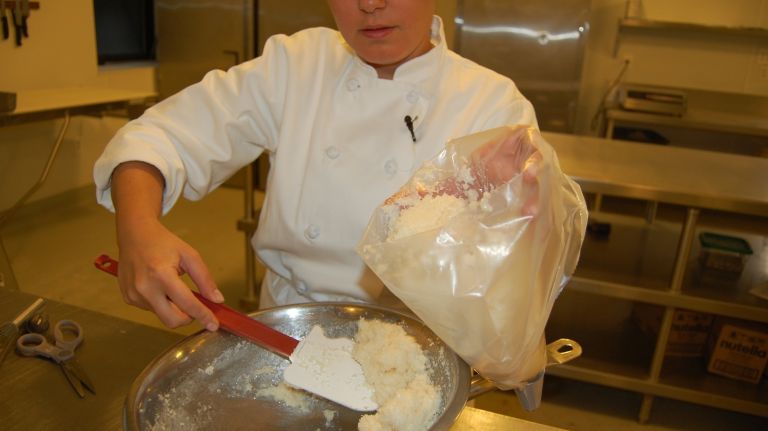Using a spatula, scoop the still warm coconut mixture into a pastry bag and push down until it's firmly packed in. 