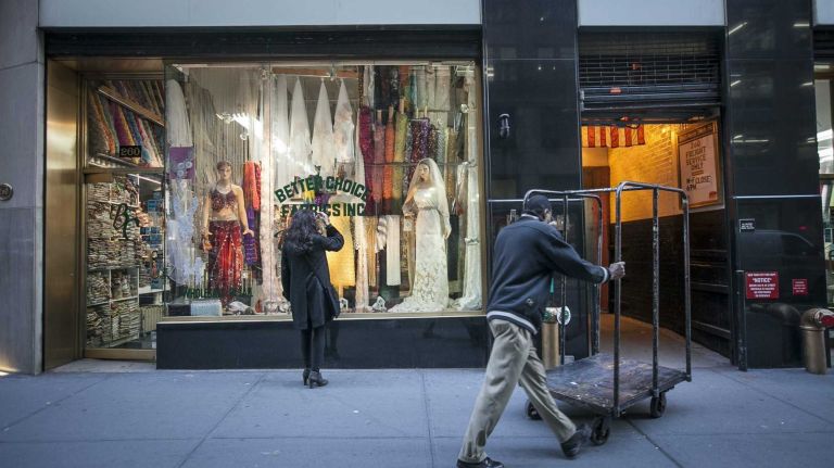 A woman looks in the window of a fabric shop on West 39th St.