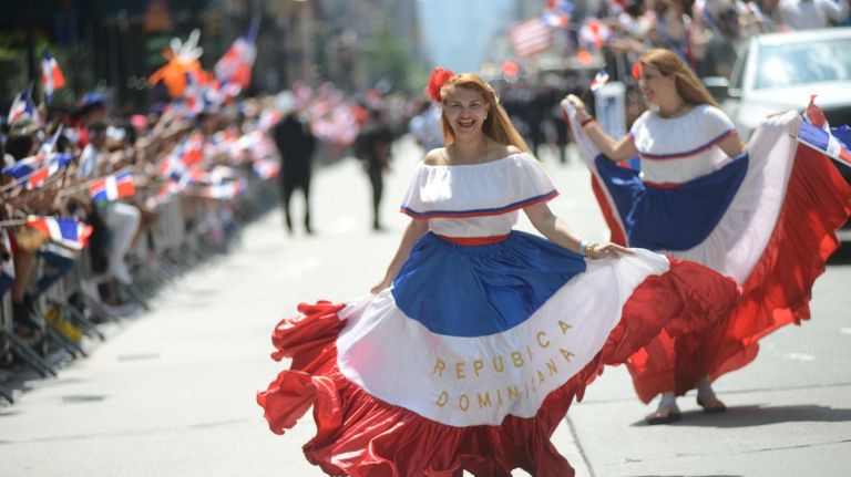 Dominican Day Parade brings color to a cloudy New York City 10 Women in bright costumes dance their way down the street.
