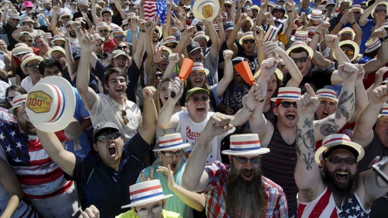 Fans cheer as they wait for the start of Nathan's Famous Fourth of July International Hot Dog Eating Contest in Coney Island, Brooklyn, on Monday, July 4, 2016. This year marks the 100th anniversary of the annual Fourth of July hot dog eating contest.