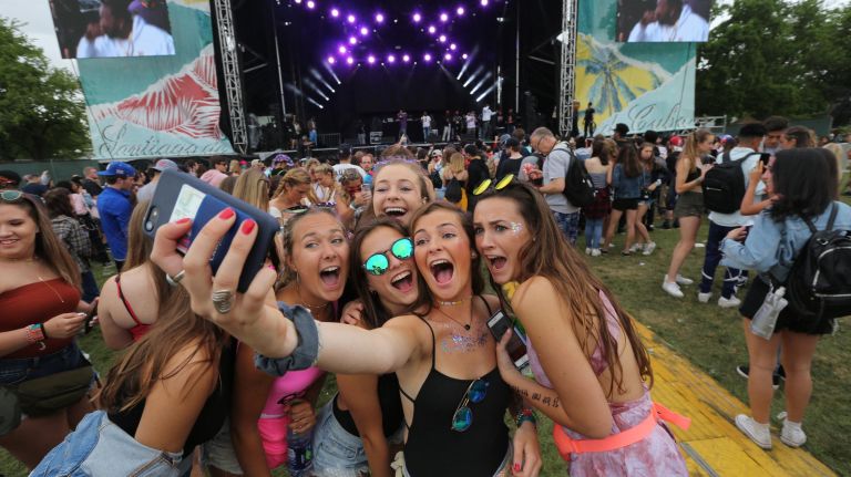 Friends take selfies as Westside Gunn and Conway perform in the background.