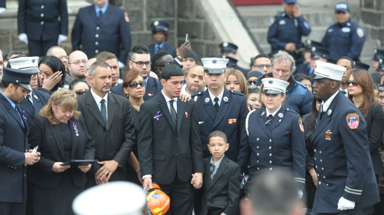 The sons of FDNY EMT Yadira Arroyo stand outside the church Saturday, March 25, 2017, after her funeral at St. Nicholas of Tolentine Church in the Bronx. With them, at left, is Arroyo's mother, Iaida Avevedo-Rosado. One son, Kenneth Robles, 19, holds his mother's helmet, which had been presented to him. Arroyo's youngest son, Isaiah Negron, 7, holds Robles' hand.