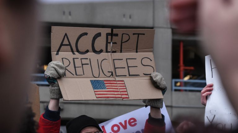 Protesters at Kennedy Airport hold signs against the suspension of the country's refugee program. 