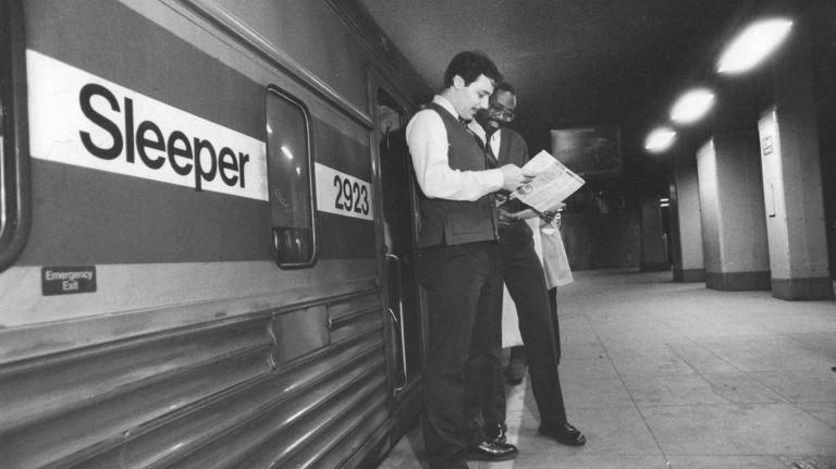 Amtrak's Chris Byrne and Markus Moore talk over preparations outside the company's executive sleeper service car before its trip from New York to Washington, D.C., in November 1985. The sleeper car held 22 passengers who were able to sleep in the train for part of the night before leaving for Washington early in the morning.
