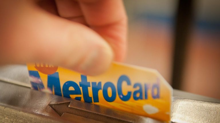 A commuter slides a MetroCard  through the turnstile.