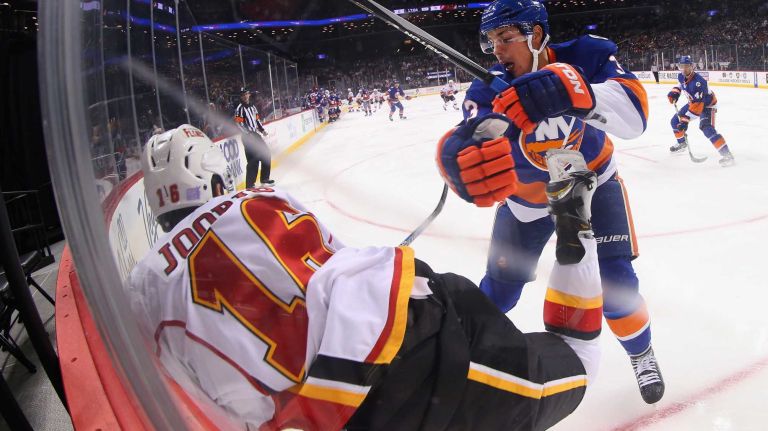 Travis Hamonic #3 of the New York Islanders checks Josh Jooris #16 of the Calgary Flames into the boards during the first period at the Barclays Center on October 26, 2015 in the Brooklyn borough of New York City. 