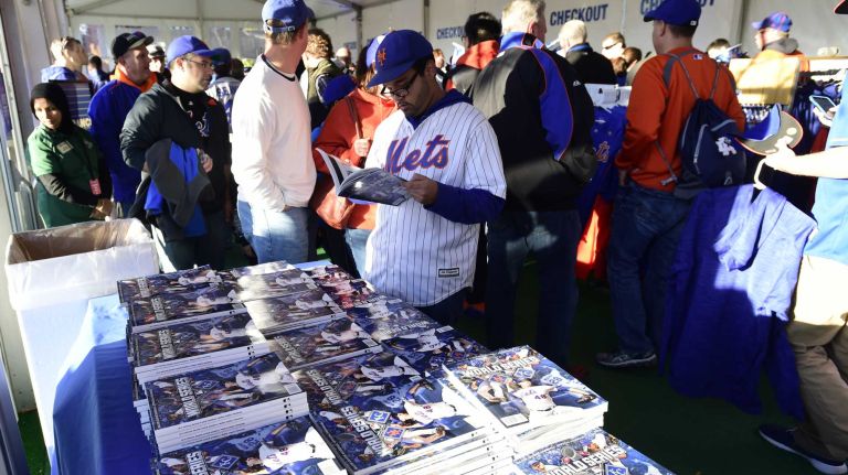 New York Mets fan Carlos Iturralde of Jersey City looks over the World Series program as fans pack the merchandise tent to grab souvenirs before Game 3 of the World Series against the Kansas City Royals at Citi Field on Friday, Oct. 30, 2015.
