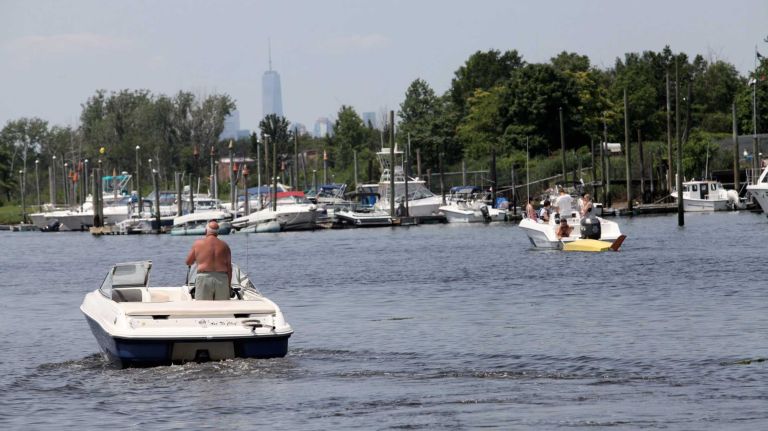 Bergen Beach 44 Tommy Panchianco, member of the Hudson River Yacht Club, left, in his boat in the Paerdegast Basin with a view of the Freedon Tower in the background, in Bergen Beach, Brooklyn, July 3, 2015.