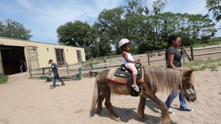 Bergen Beach 59 Danielle Tynes, takes her daughter, Kennedy, 3, on a pony ride at the Jamaica Bay Riding Academy in Bergen Beach, Brooklyn, July 3, 2015.
