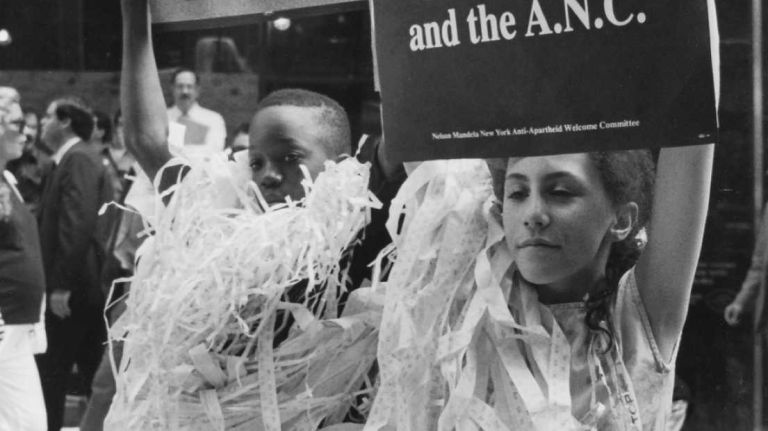 Buried in ticker tape, Aaron Williams and Gena Oppenheim from P.S. 10 welcome Nelson Mandela to New York along the parade route on Broadway near Bowling Green. (June 20, 1990)