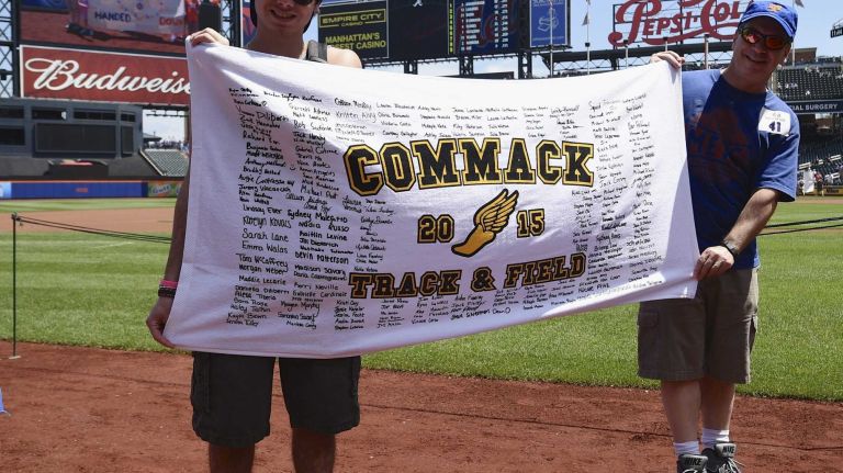 New York Mets fans walk with banners along the warning track at Citi Field on Banner Day before a baseball game between the Mets and the Atlanta Braves on Sunday, June 14, 2015.