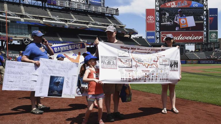 New York Mets fans walk with banners along the warning track at Citi Field on Banner Day before a baseball game between the Mets and the Atlanta Braves on Sunday, June 14, 2015.