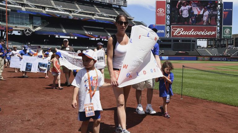 New York Mets fans walk with banners along the warning track at Citi Field on Banner Day before a baseball game between the Mets and the Atlanta Braves on Sunday, June 14, 2015.