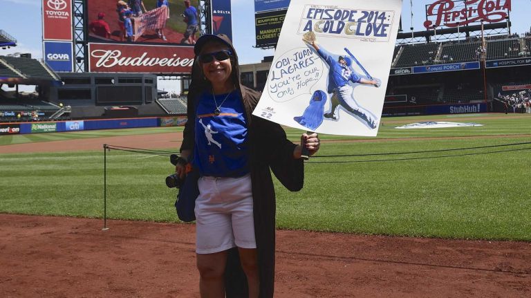 New York Mets fans walk with banners along the warning track at Citi Field on Banner Day before a baseball game between the Mets and the Atlanta Braves on Sunday, June 14, 2015.