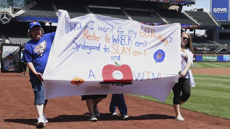 New York Mets fans walk with banners along the warning track at Citi Field on Banner Day before a baseball game between the Mets and the Atlanta Braves on Sunday, June 14, 2015.