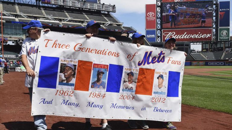 New York Mets fans walk with banners along the warning track at Citi Field on Banner Day before a baseball game between the Mets and the Atlanta Braves on Sunday, June 14, 2015.