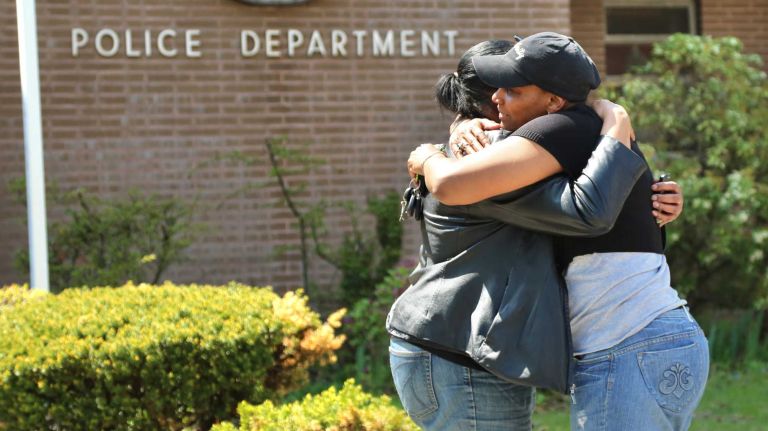 A police officer, right, and another woman comfort each other outside the 105th Precinct in Queens Village after hearing that Police Officer Brian Moore passed away on Monday, May 4, 2015.