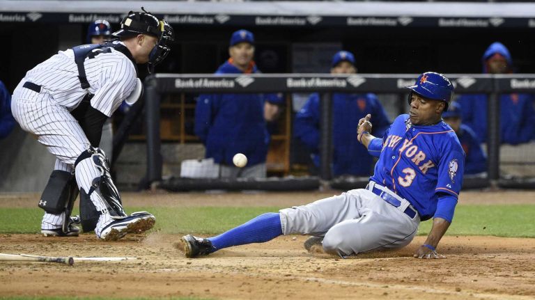 New York Mets rightfielder Curtis Granderson scores as New York Yankees catcher Brian McCann waits for the throw in a baseball game at Yankee Stadium on Friday, April 24, 2015.
