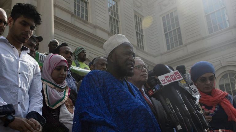 Members of the Muslim community and other religious faiths pray together Thursday, Aug. 18, 2016, on the steps of City Hall in Manhattan after a news conference regarding the fatal shootings of an imam and an aide.  