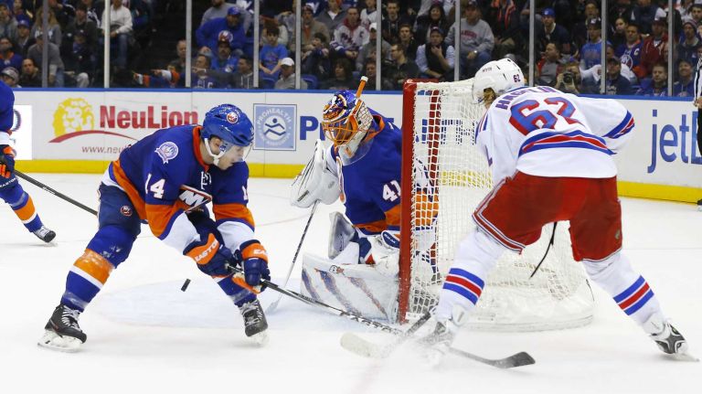 Jaroslav Halak and Thomas Hickey of the New York Islanders defend the net in the second period against Carl Hagelin of the New York Rangers at Nassau Coliseum on Tuesday, March 10, 2015.