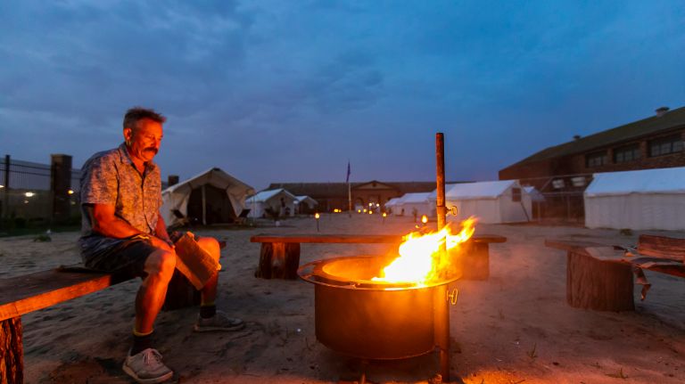Camp Rockaway co-manager Wade Mayer is fireside on the grounds of the Jacob Riis Park Bathhouse on Friday.