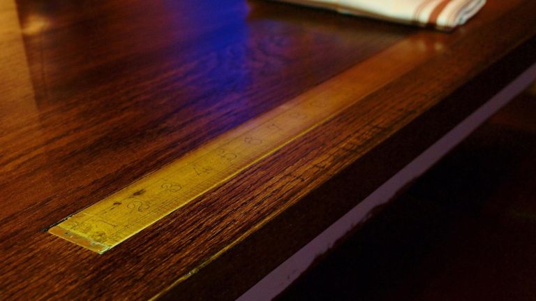 ...tailors' rulers, embedded in the wooden tables near the main bar. 