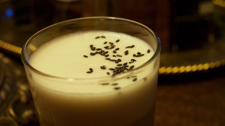 Whipped egg whites give this scotch cocktail its frothiness. Japanese yuzu lends a light citrus flavor, caramel a slight sweetness, but sesame is dominant. A sprinkling of black sesames brings the 