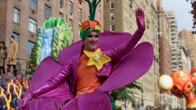 A performer on stilts and dressed as a flower waves to spectators along Central Park West on Thursday, Nov. 24, 2016, at the start of the 90th annual Macy's Thanksgiving Day Parade in Manhattan.