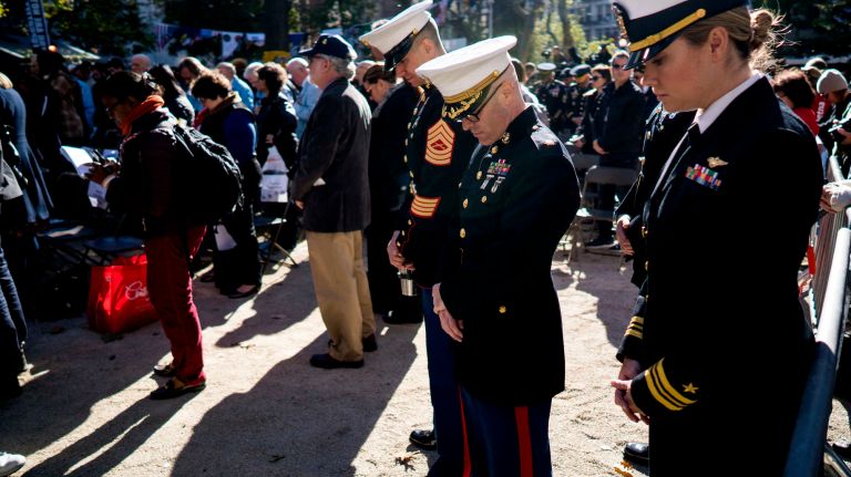 Members of the Marines and Navy bow their heads doing a prayer as they gather in Madison Square Park for a service during the Veterans Day Parade in Manhattan on Friday, Nov. 11, 2016.