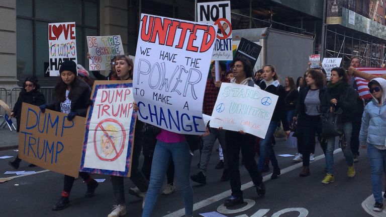 Demonstrators hold signs as they march to Trump Tower along Fifth Avenue in Manhattan on Saturday, Nov. 12, 2016, protesting against President-elect Donald Trump.