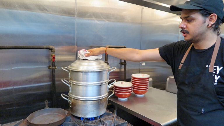 Executive chef Carlos Barrera steams the house-made bao buns for the Hong Kong Fried Chicken Sandwich while the chicken is frying, sprinkling a few sesame seeds on top partway through the process.