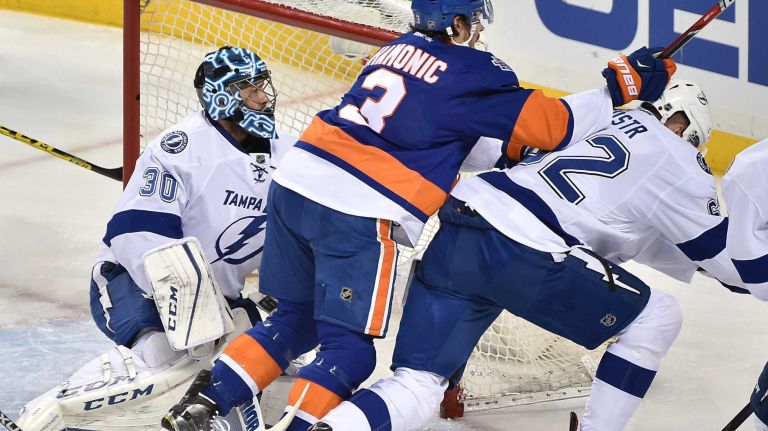 Tampa Bay Lightning goalie Ben Bishop (30) defends the goal as New York Islanders defenseman Travis Hamonic (3) checks Tampa Bay Lightning defenseman Andrej Sustr (62) in the first period in Game 3 of the Eastern Conference semifinals on Tuesday, May 3, 2016 at Barclays Center.