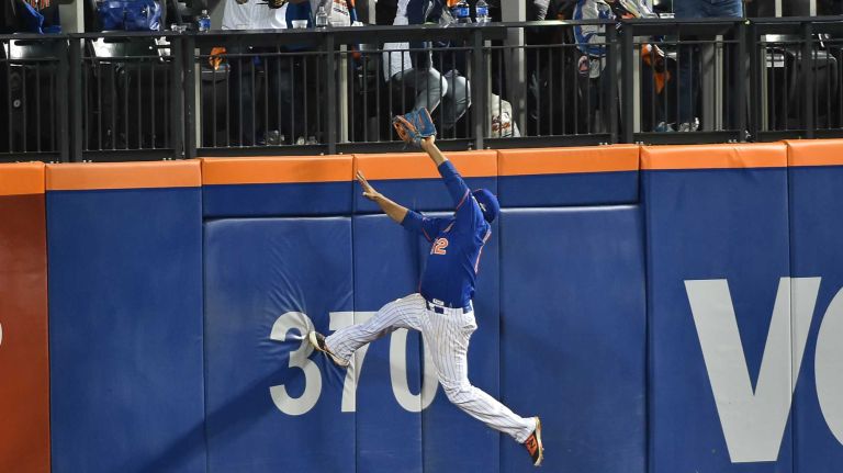 New York Mets center fielder Juan Lagares (12) leaps in vain as Los Angeles Dodgers first baseman Adrian Gonzalez (23) smacks a solo homer in the 7th inning as the Mets vs. Dodgers at Citi Field in Queens during Game 3 of the NLDS on Monday, Oct. 12, 2015.