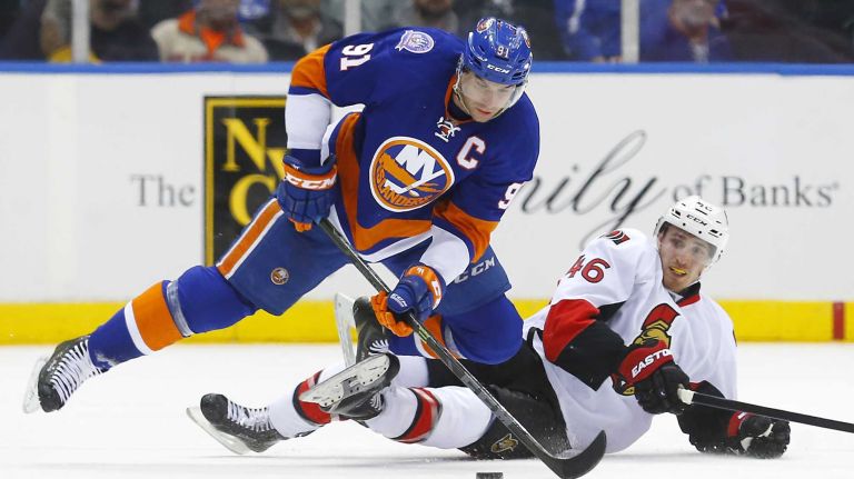 John Tavares of the New York Islanders battles for the puck in the second period against Patrick Wiercioch of the Ottawa Senators at Nassau Coliseum on Friday, March 13, 2015.