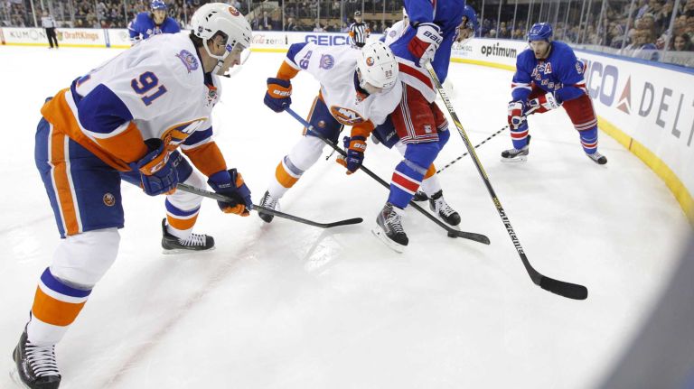 John Tavares and Brock Nelson of the New York Islanders play the puck against Ryan McDonagh of the New York Rangers at Madison Square Garden on Tuesday, Jan. 13, 2015.