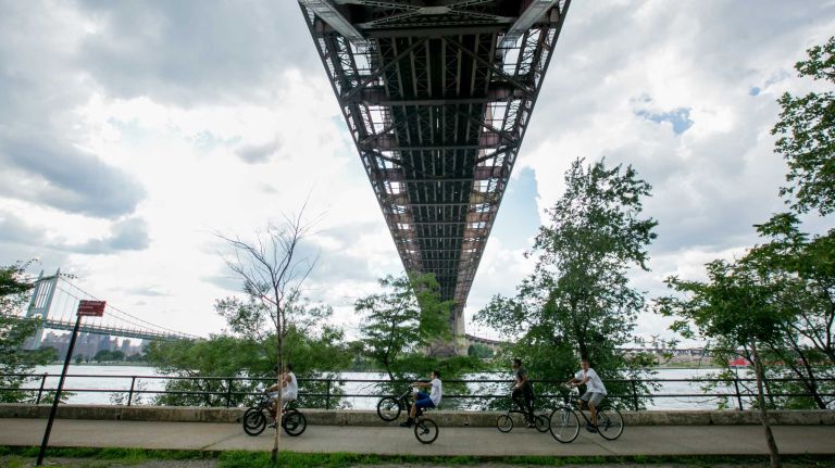 People walk under the Hells Gate Bridge along the East River in Astoria on July 17, 2014.