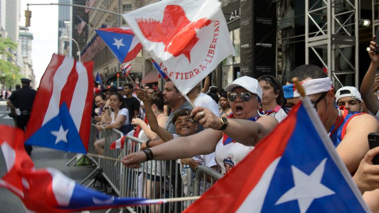 Spectators cheer and wave flags during the Puerto Rican Day Parade on Sunday, June 11, 2017. 
