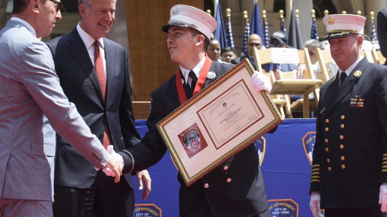 FDNY Lt. John Haseney, of West Islip, center, shakes hand with Fire Commissioner Daniel A. Nigro, left, and New York City Mayor Bill de Blasio, second from left, after receiving the Henry D. Brookman Medal during the FDNY Medal Day Ceremony in front of City Hall in Manhattan on Wednesday, June 01, 2016. Lt. Haseney, a former member of the New York Army National Guard who was deployed to Afghanistan in 2008, rescued a woman during a fire in Queens in 2015.