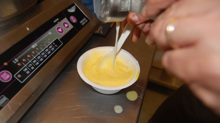 While whisking, slowly pour in ½ cup of the hot milk mixture to temper the egg yolks. Continue to whisk slowly until the mixture is an even color and consistency.