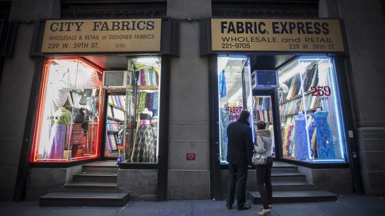 People look in the window of a fabric store on West 39th St.