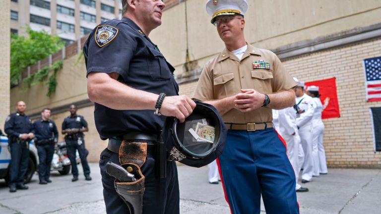 A soon to be retired service revolver hangs on the gunbelt of NYPD police officer Paul Sulzbach as he speaks with Marine Maj. Dan Nardiello while they attend a Memorial Day function at Sulzbach's precinct on May 28, 2018.