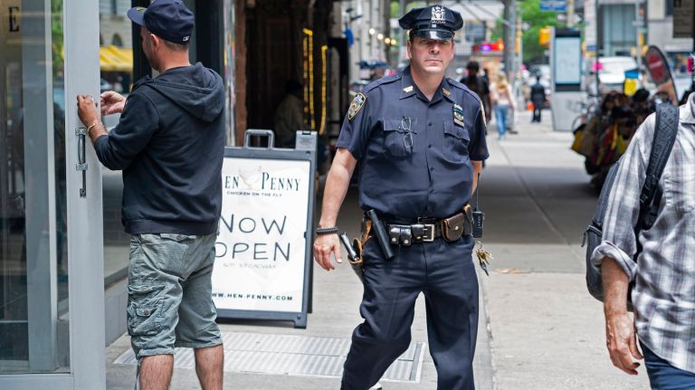 NYPD Officer Paul Sulzbach walks along Broadway in midtown on Monday, with his soon-to-be-retired service revolver. 