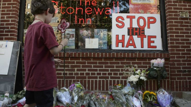 Nicholas Brown-Spino places a handmade flower in front of the Stonewall Inn in Manhattan at a vigil for the victims of the mass shooting attack in Orlando, Fla., on Sunday, June 12, 2016. A gunman armed with an assault rifle and handgun killed 49 people and wounded 53 at Pulse, a gay nightclub in Orlando, in what officials termed the worst mass shooting in U.S. history.