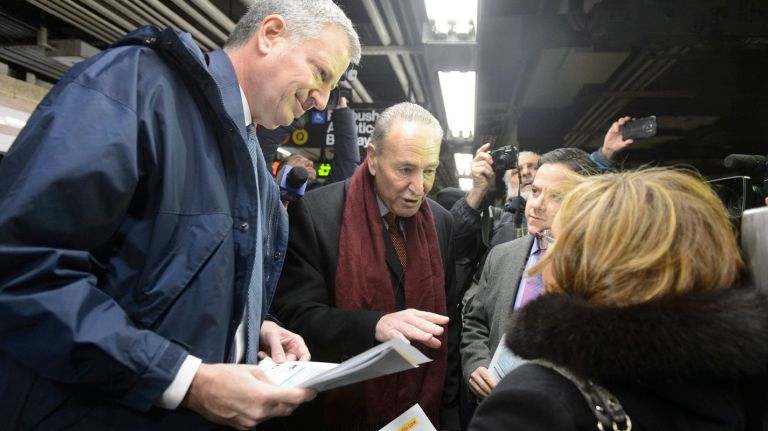 New York City Mayor Bill de Blasio, left, and U.S. Senator Charles E. Schumer, center, pass out fliers on the new commuter benefits law at the Atlantic Avenue-Barclays Center subway station in Brooklyn on Monday, Jan. 4, 2016. 