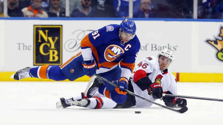 John Tavares of the New York Islanders battles for the puck in the second period against Patrick Wiercioch of the Ottawa Senators at Nassau Coliseum on Friday, March 13, 2015.